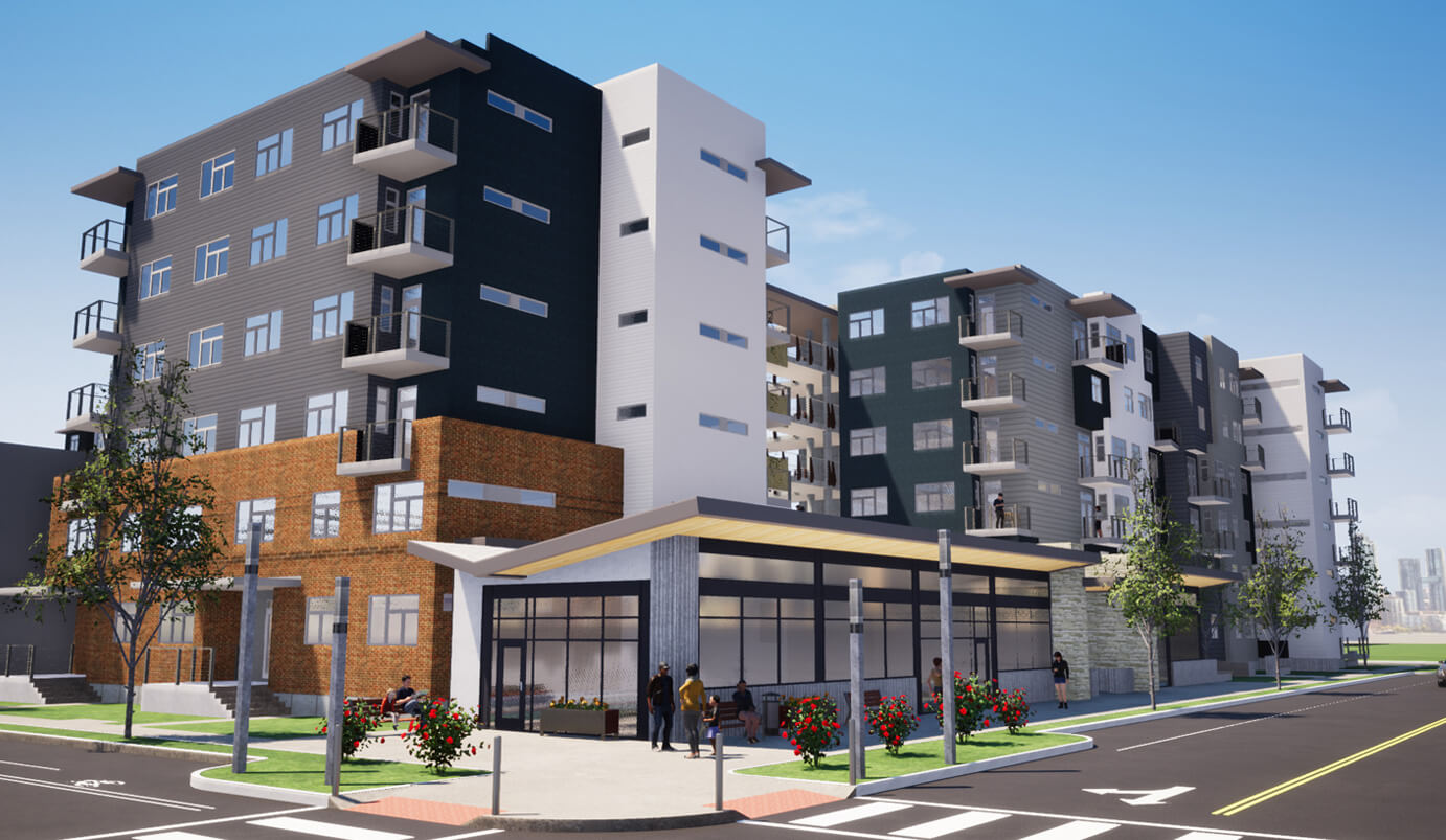 A modern multi-story apartment complex with balconies, brick and gray facades, and a covered bus stop in front. People are waiting at the stop and walking on the sidewalk under a clear blue sky.