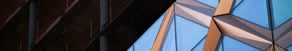 Abstract architectural design featuring triangular glass panels reflecting blue and brown hues. The left side showcases vertical metal beams in shadow, contrasting with the illuminated geometric glass pattern on the right, reminiscent of a master architects vision realized through Graphisoft CAD.
