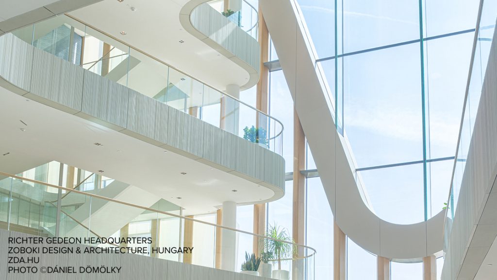 A bright, modern atrium with curved white balconies, glass walls of Richter Gideon headquarters motivates students to innovate by using cutting-edge technology of Graphisoft